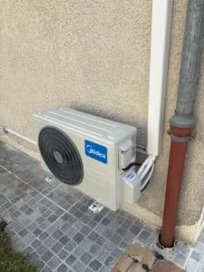 Unité extérieure midéa réversible fixée sur mur maison à Meylan